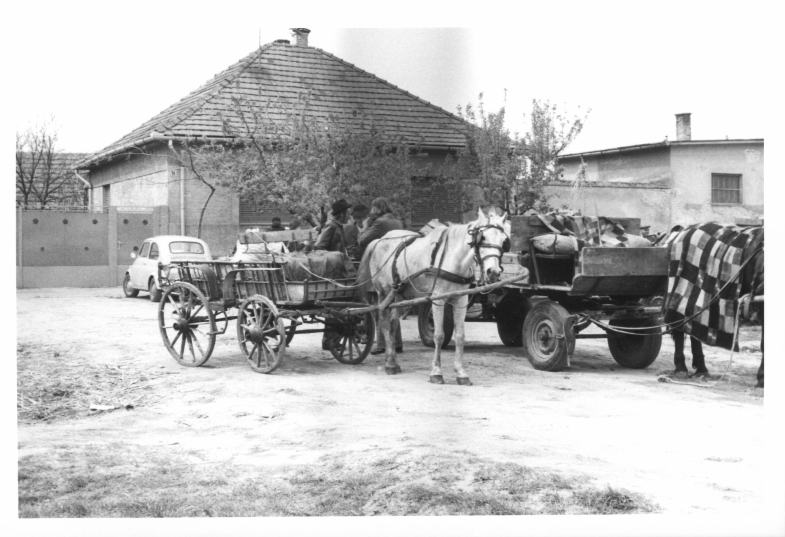 An old cart in front of a modern house in the village centre, 1977